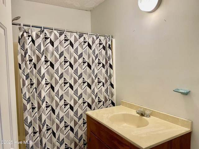 bathroom with curtained shower, vanity, and a textured ceiling