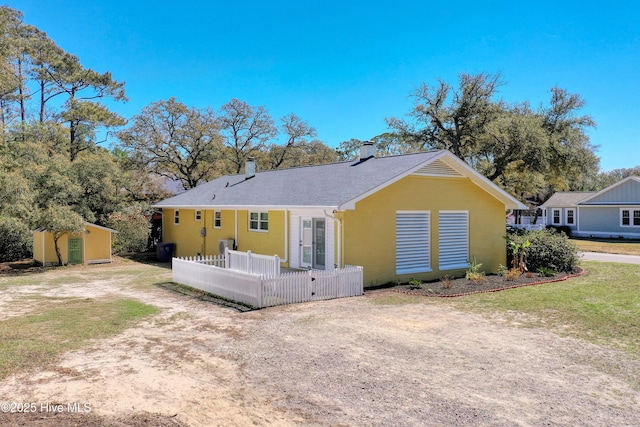 302 NE 60th St, Oak Island, NC 28465 - rear view of house featuring a chimney, fence, an outbuilding, and a storage shed