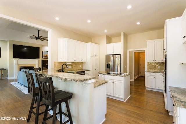 86 Sakonnet Trl, Pinehurst, NC 28374 - kitchen with black appliances, a ceiling fan, a peninsula, decorative backsplash, and dark wood-style floors