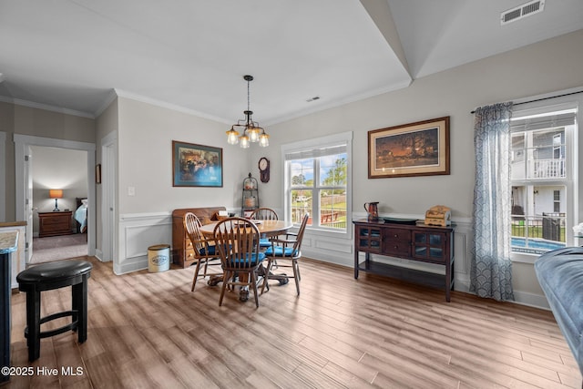 442 Crows Nest Ln, Sneads Ferry, NC 28460 - dining area featuring light wood-style floors, wainscoting, a chandelier, crown molding, and a decorative wall