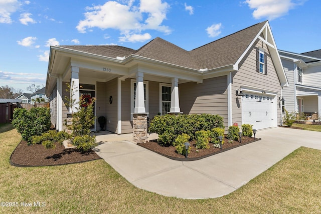 craftsman house featuring a garage, a front lawn, covered porch, roof with shingles, and driveway