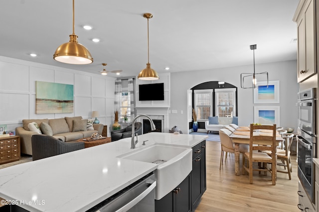 kitchen featuring light wood-type flooring, open floor plan, a fireplace, and a sink