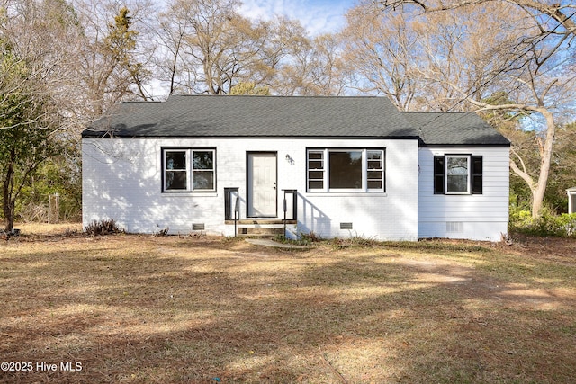 view of front facade featuring brick siding, crawl space, and roof with shingles