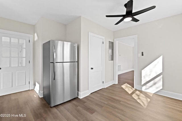 kitchen featuring freestanding refrigerator, wood finished floors, a ceiling fan, and baseboards