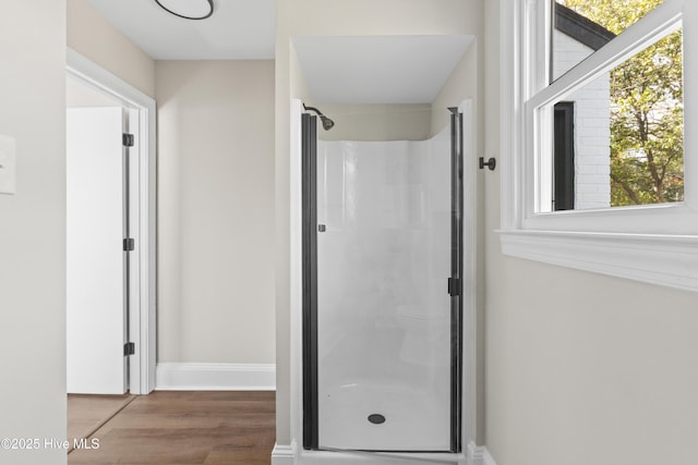 bathroom with a shower stall, baseboards, and wood finished floors