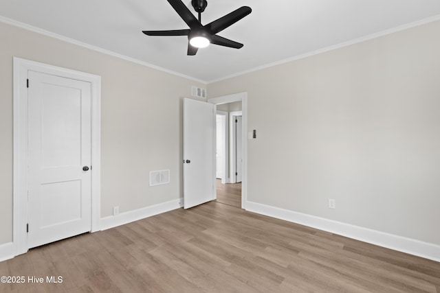 unfurnished bedroom with light wood-style flooring, visible vents, baseboards, and ornamental molding