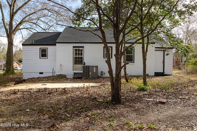 back of property featuring crawl space, a shingled roof, brick siding, and central AC unit
