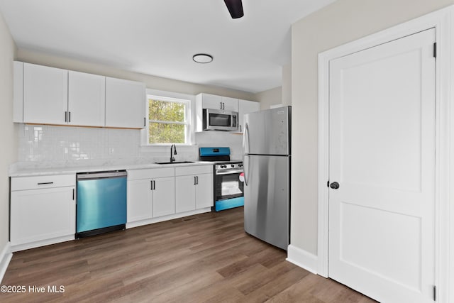 kitchen featuring a sink, decorative backsplash, white cabinetry, light countertops, and appliances with stainless steel finishes