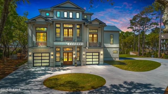 view of front of house with a garage, metal roof, french doors, and curved driveway