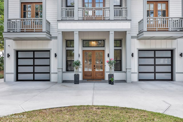 doorway to property with driveway, board and batten siding, french doors, and an attached garage
