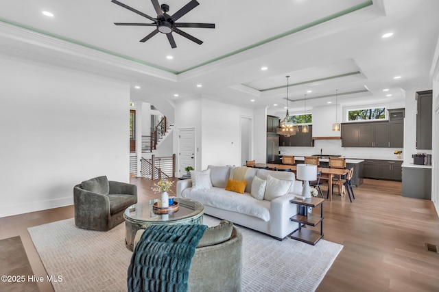 living room featuring recessed lighting, ceiling fan, crown molding, and a raised ceiling