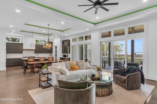 living room featuring recessed lighting, a tray ceiling, a ceiling fan, and wood finished floors