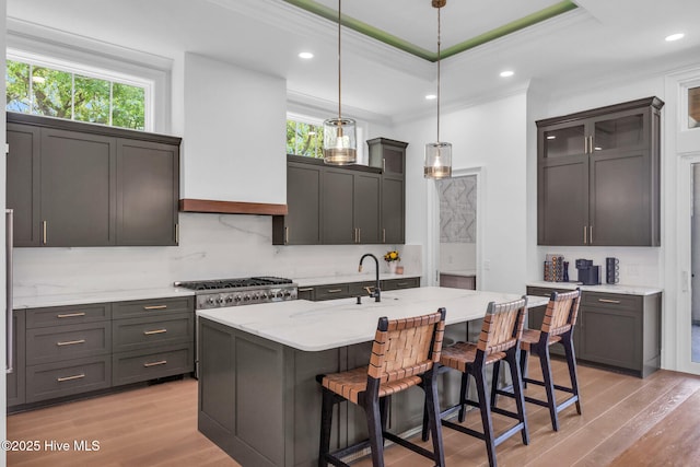 kitchen featuring a breakfast bar, ornamental molding, decorative light fixtures, light wood-style floors, and a sink