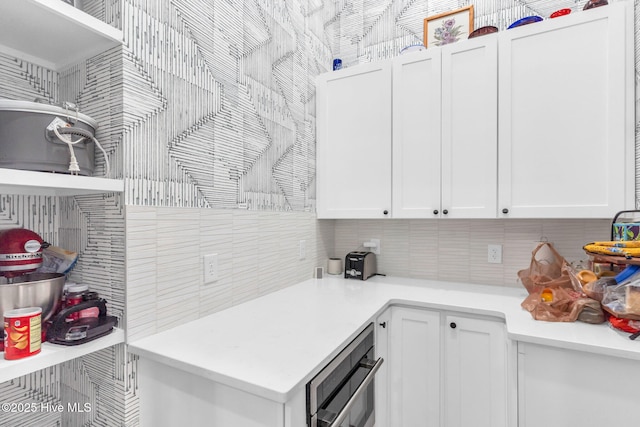 kitchen with decorative backsplash, light countertops, and white cabinets