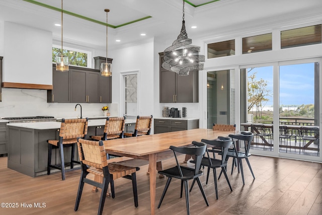 dining room featuring light wood-style floors, a high ceiling, and ornamental molding