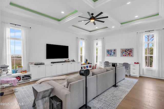 living area with coffered ceiling, a ceiling fan, and a wealth of natural light