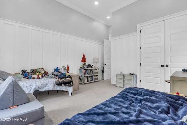 carpeted bedroom with a decorative wall, a wainscoted wall, recessed lighting, and crown molding