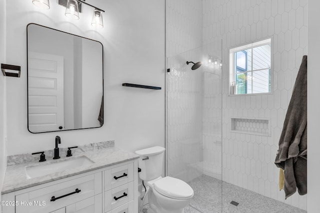 full bath featuring toilet, tiled shower, and vanity