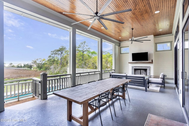 sunroom featuring outdoor dining space, a ceiling fan, and exterior fireplace