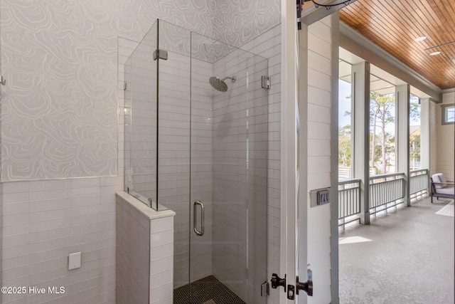 bathroom featuring a shower stall, crown molding, wallpapered walls, and a wainscoted wall