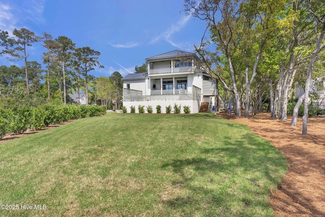 view of front of house featuring metal roof, a balcony, and a front lawn