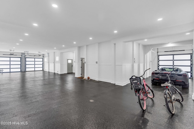garage featuring recessed lighting, a decorative wall, and a wainscoted wall