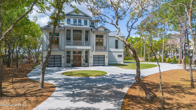 view of front of home featuring an attached garage, board and batten siding, a balcony, french doors, and curved driveway