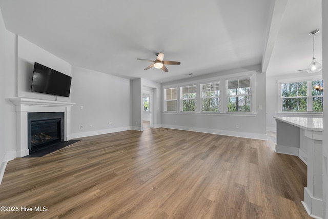 7801 Harrier Cir, Leland, NC 28451 - unfurnished living room featuring a fireplace with flush hearth, baseboards, a ceiling fan, and wood finished floors
