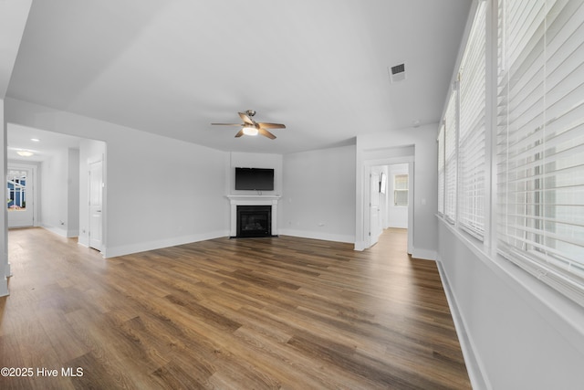 7801 Harrier Cir, Leland, NC 28451 - unfurnished living room with a fireplace with flush hearth, dark wood-style flooring, baseboards, and ceiling fan
