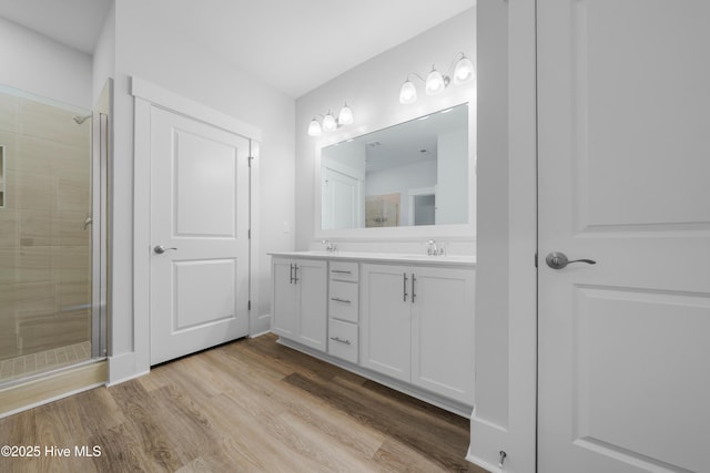 7801 Harrier Cir, Leland, NC 28451 - bathroom with a sink, double vanity, a stall shower, and wood finished floors