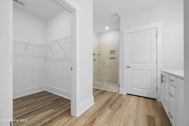 7801 Harrier Cir, Leland, NC 28451 - full bathroom with a walk in closet, visible vents, a shower stall, and wood finished floors