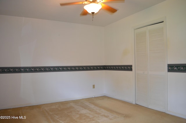 spare room with light colored carpet and a ceiling fan