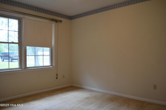 empty room featuring baseboards and light carpet
