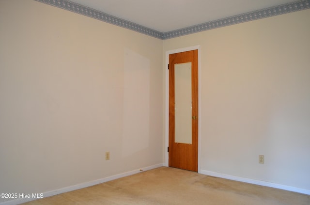 empty room featuring baseboards and light colored carpet
