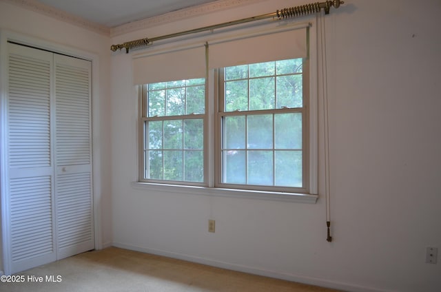 unfurnished bedroom with light carpet, a closet, and multiple windows