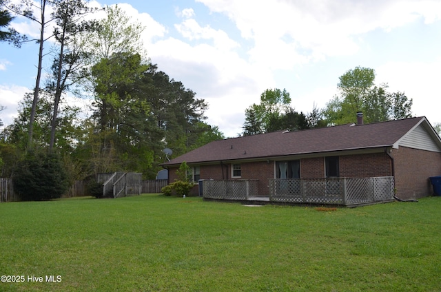 back of property with brick siding, a wooden deck, and a lawn