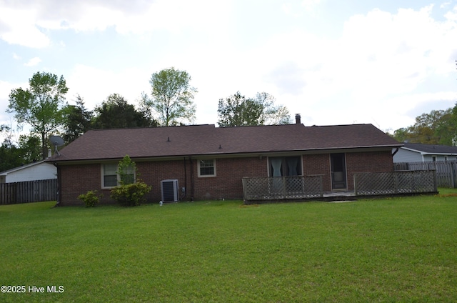rear view of house featuring central AC unit, a yard, fence, and brick siding