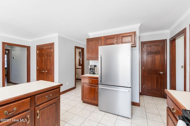 kitchen with light tile patterned flooring, freestanding refrigerator, light countertops, and ornamental molding