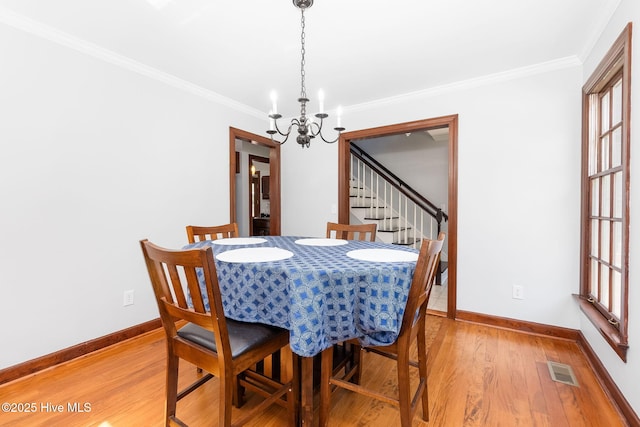 dining room featuring a chandelier, light wood-type flooring, visible vents, and stairs