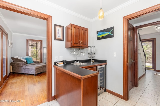 bar with indoor wet bar, baseboards, a sink, and crown molding