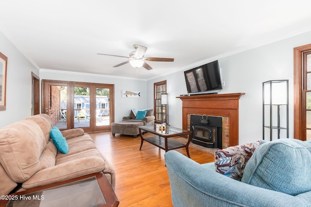 living area with crown molding, light wood finished floors, ceiling fan, and a wood stove