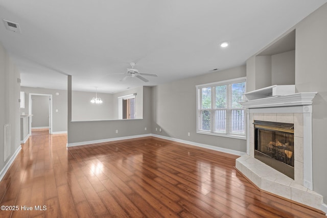 424 Commerce Ave Unit B, Morehead City, NC 28557 - unfurnished living room with hardwood / wood-style flooring, visible vents, baseboards, a tiled fireplace, and ceiling fan with notable chandelier