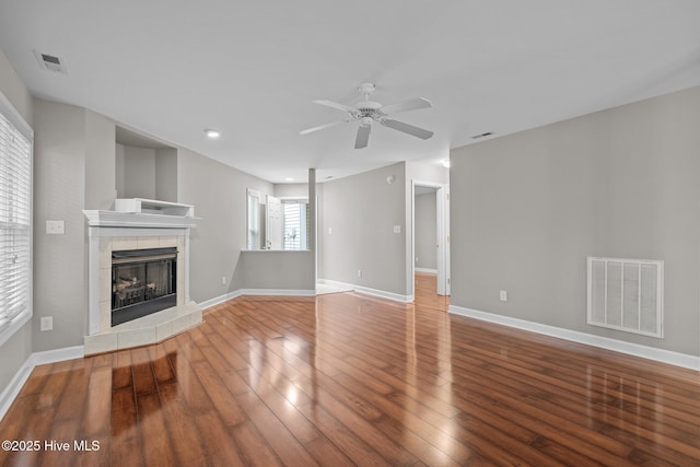 424 Commerce Ave Unit B, Morehead City, NC 28557 - unfurnished living room featuring visible vents, a ceiling fan, wood-type flooring, baseboards, and a tiled fireplace