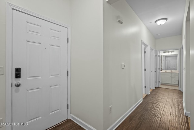 hallway featuring baseboards and dark wood-style flooring