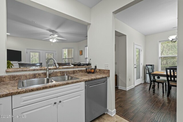 kitchen with ceiling fan with notable chandelier, stainless steel dishwasher, a sink, white cabinets, and wood finished floors