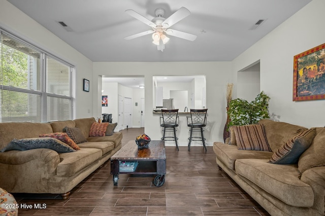 living area with a ceiling fan, wood tiled floor, and visible vents