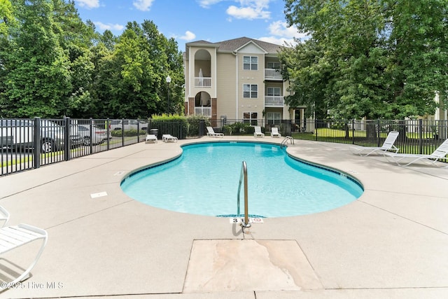 community pool with fence and a patio
