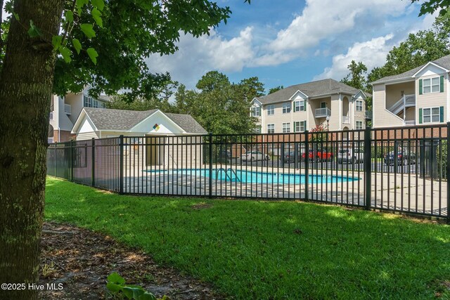 community pool featuring a yard, a patio area, fence, and a residential view