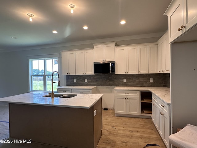 163 Noramac Ct, Selma, NC 27576 - kitchen featuring stainless steel microwave, light stone counters, decorative backsplash, light wood-type flooring, and white cabinets