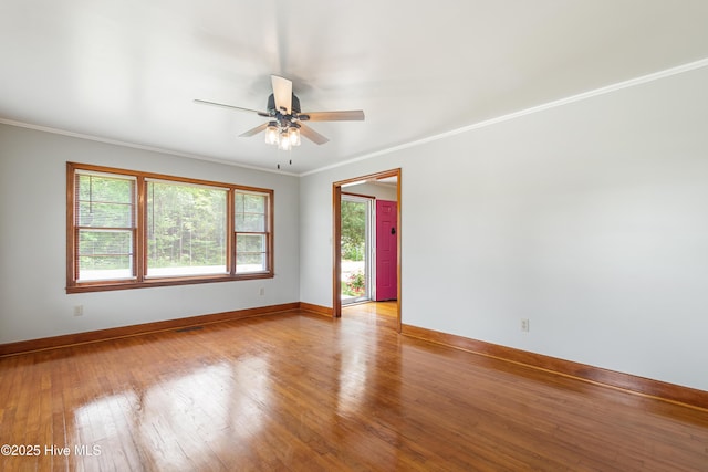 spare room with baseboards, ceiling fan, wood-type flooring, and crown molding